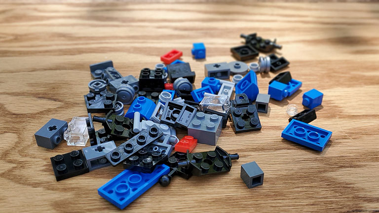 A pile of Lego bricks, all mixed up, unsorted, like someone just dumped out the bag on a table.